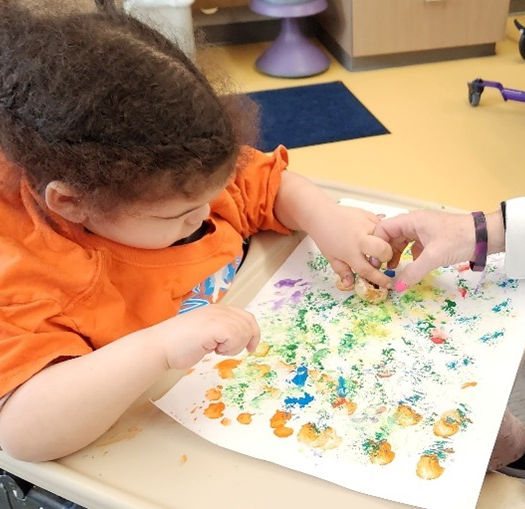 A young girl paints using a small sponge