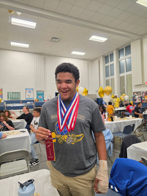 A young man smiles proudly holding his medals and ribbon earned during the Fall 2025 North Central Association of Blind Schools (NCASB) Track and Field meet in Nashville, TN.