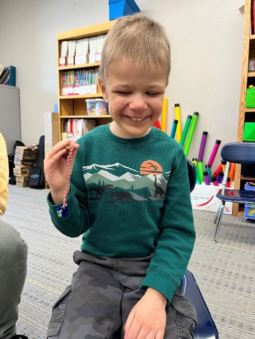 A young boy smiles while playing with a bell that has a short red cord