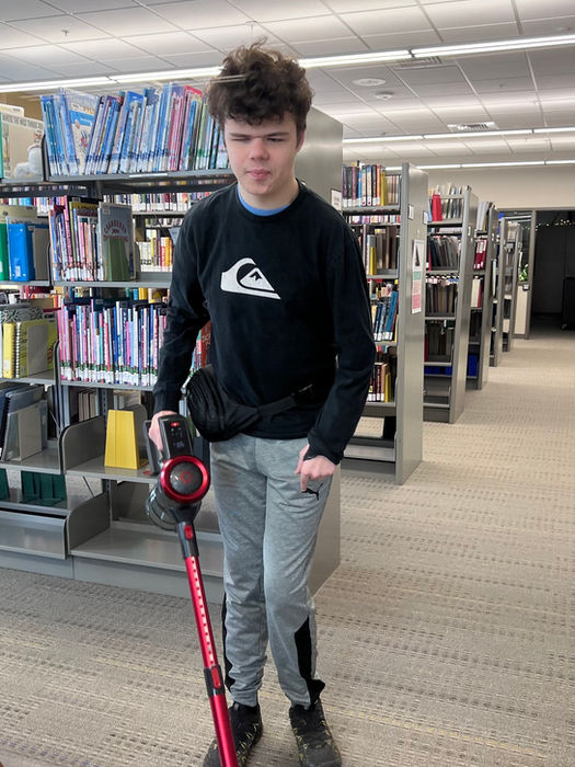 A young man independently vacuums the carpet in the library