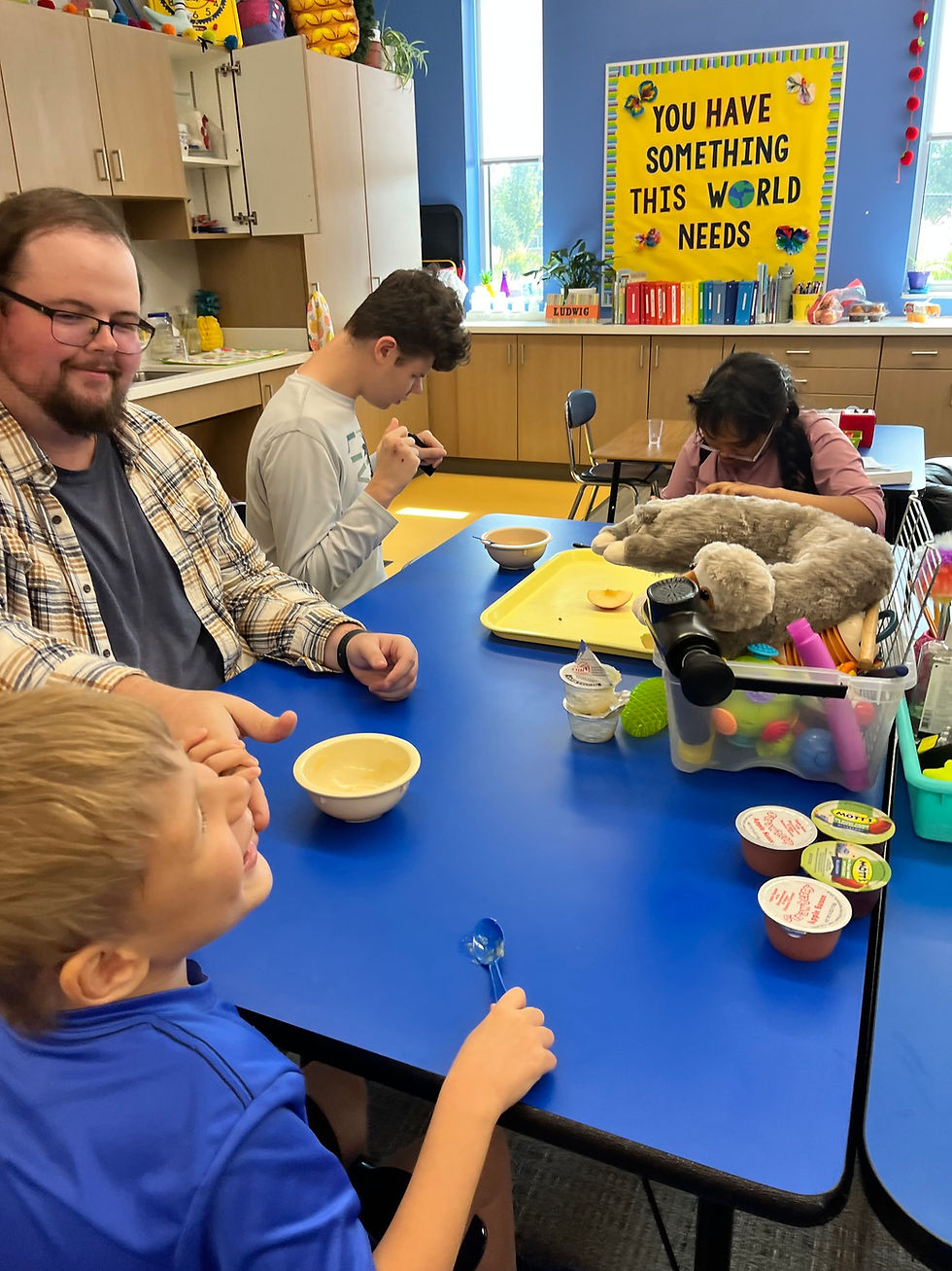 Students gathered around a table with their teacher tasting different flavors of applesauce
