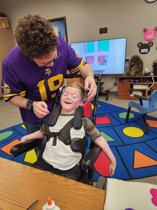 A young boy being silly with an instructional assistant as the boy shows off his cool wiggly eyes